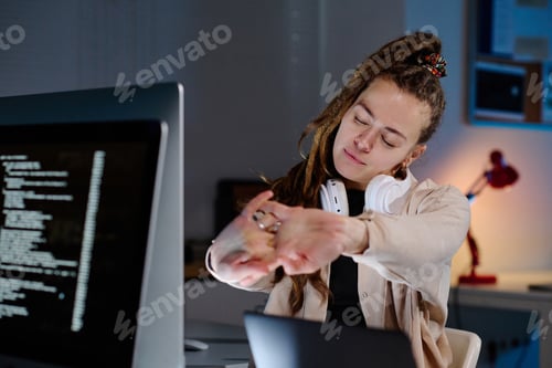 Preview: Young tired female IT support manager with dreadlocks stretching arms
