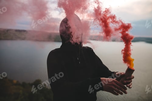 Preview: Ultras hooligan holding red smoke bomb in hand with amazing view on river