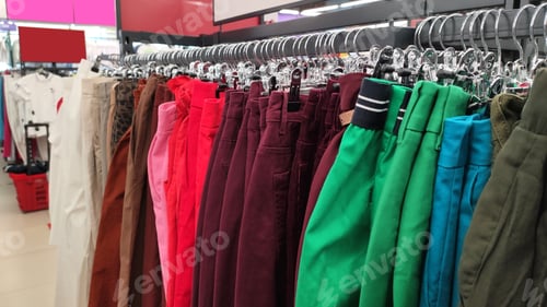 Preview: Row of different colorful pants trousers on hanger in shop,