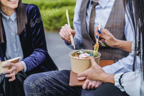 Preview: Business people eating takeaway food during lunch break outdoor outside the office