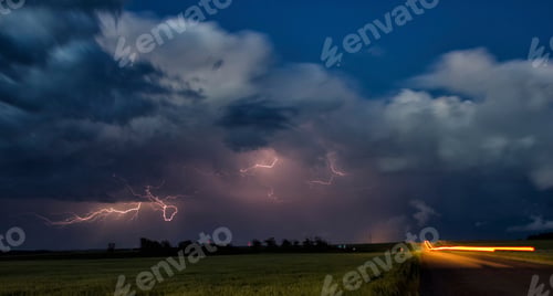 Preview: Nighttime thunderstorm with vivid lightning strikes over a field.