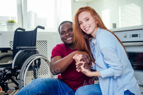 Preview: Young bearded handicapped african american man in wheelchair and his pretty wife at kichen