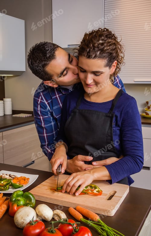 Preview: Couple hugging and preparing vegetables in the kitchen