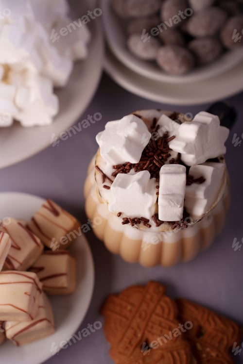 Preview: Cozy marshmallow-topped hot chocolate with sweets on soft purple surface; scrumptious closeup view.