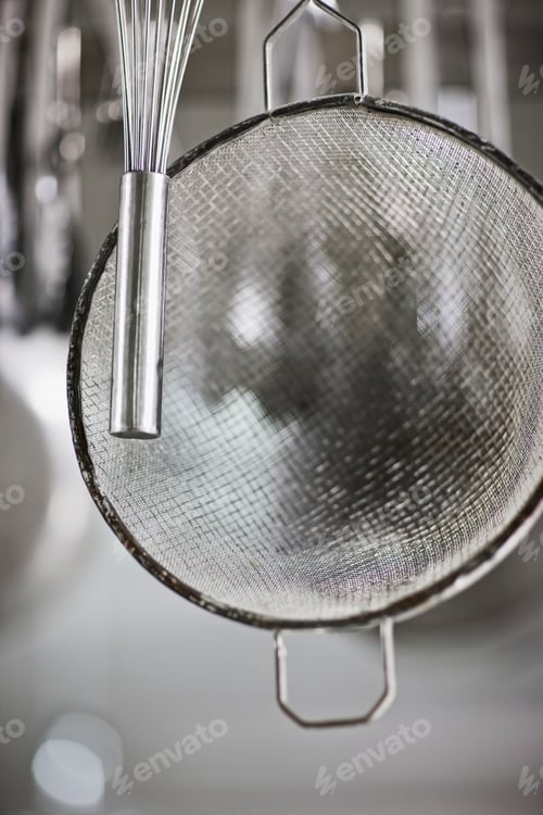 Preview: Whisk and sieve hanging in commercial kitchen.
