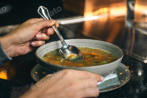 Preview: A woman in a cafe eats a low-calorie vegetable soup.