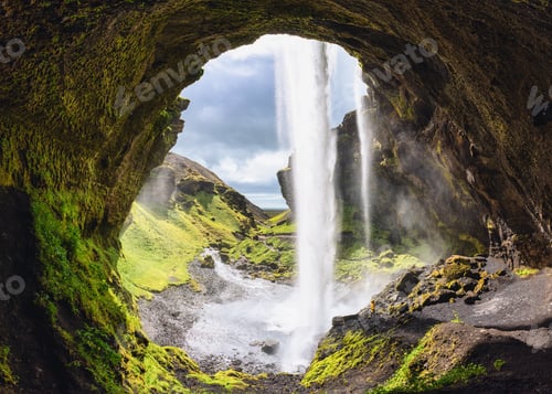 Preview: Kvernufoss waterfall flowing from cliff and hiker standing in summer at Iceland