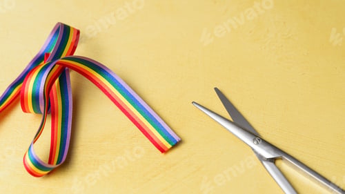 Preview: LGBT rainbow ribbon ready to be cut. Yellow background
