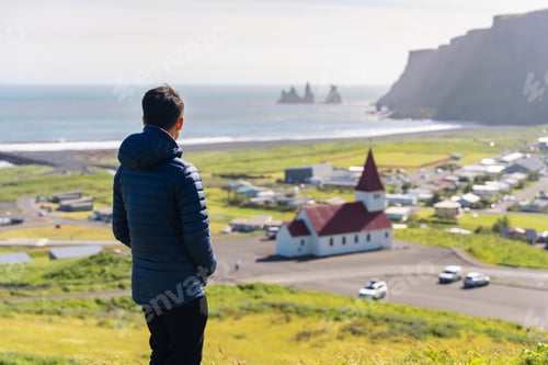 Preview: Tourist man enjoy looking view of Reyniskirkja church among the mountain near the beach