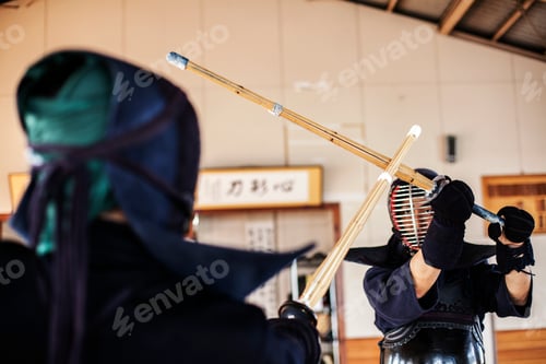 Preview: Two Japanese Kendo fighters wearing Kendo masks practicing with wood sword in gym.