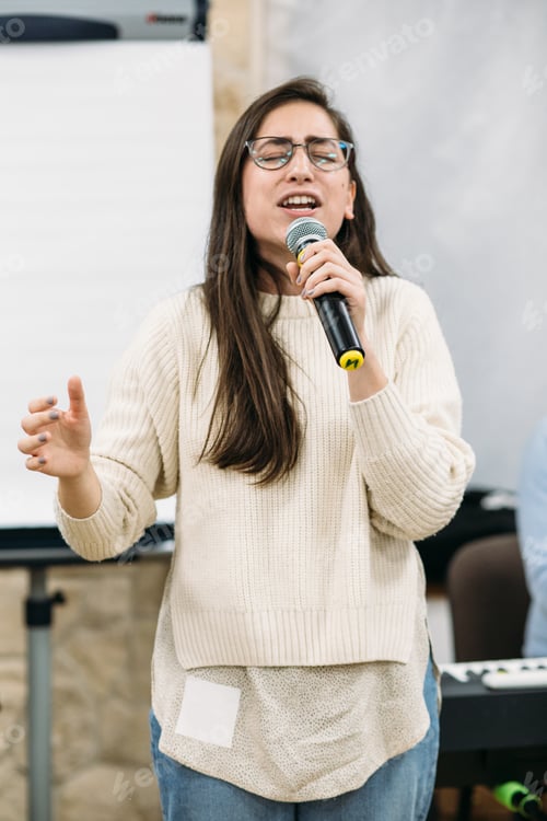 Preview: Young woman singing passionately. Time of worship and pray. Holding a microphone