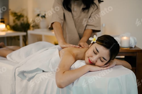 Preview: Relaxed woman lying on massage table while massage therapist massages her. Wellness concept