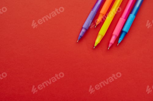 Preview: Colorful pens with caps closeup, red background
