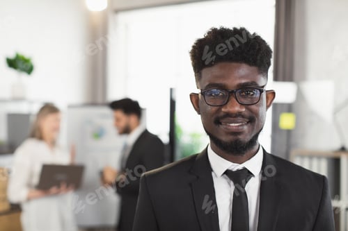Preview: African businessman in suit and eyewear posing at office