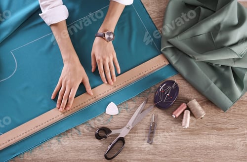 Preview: Tailor working with cloth at table in atelier, top view