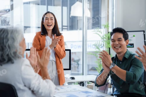 Preview: Asian businesspeople clapping hands during a meeting in the office