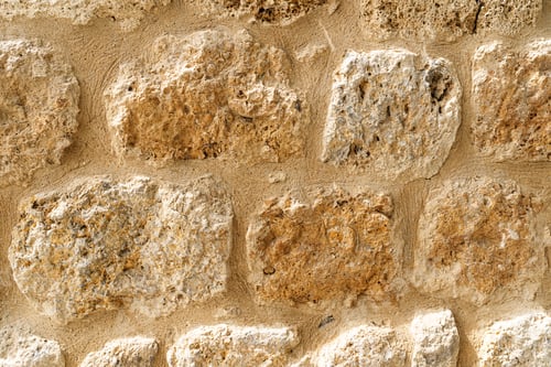 Preview: Old beige stone wall background texture close up. Castle wall surface, antique natural stonewall