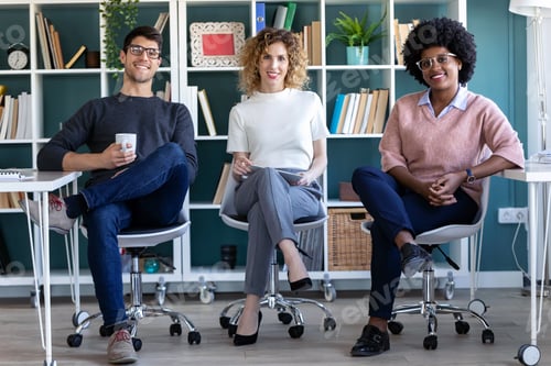 Preview: Casual young business people looking at camera while working in the new office.