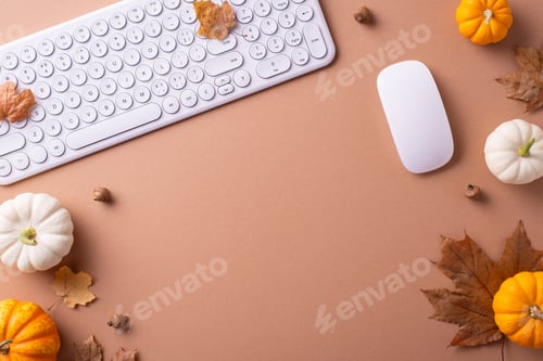 Preview: Flat lay of a beige workspace with a white keyboard and mouse surrounded by pumpkins