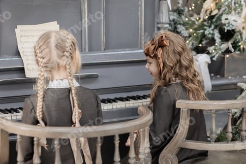 Preview: Two 5-6-year-old girls are learning to play the piano in the New Year decorations, in retro style