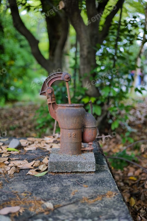 Preview: Vertical shot of an antique hand water pump in the forest