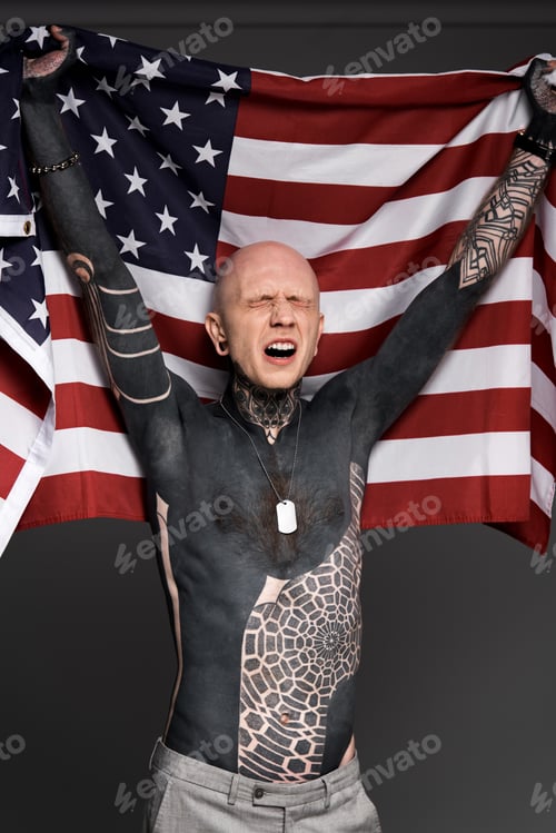 Preview: emotional tattooed man with closed eyes holding us flag isolated on grey