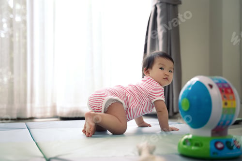 Preview: Asian cute scamp baby crawling on soft mat at home and turning look back to see what happen.