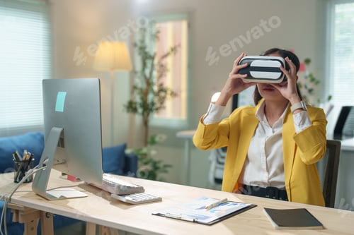 Preview: Asian businesswoman wearing virtual reality headset experiencing metaverse technology in modern offi