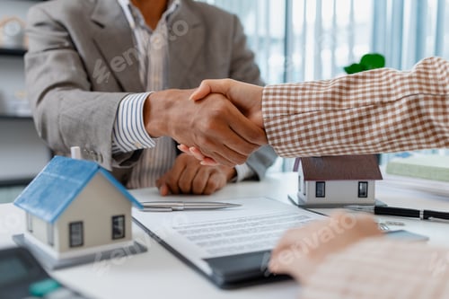 Preview: Two people in business attire finalize a real estate deal, shaking hands across a desk