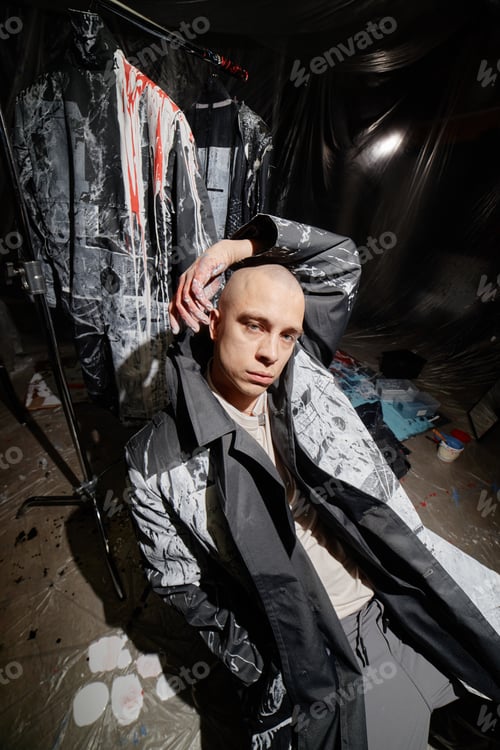 Preview: Male Fashion Artist Posing in Coat Painted with Abstract Pattern in Workshop