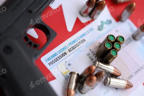 Preview: Canadian firearms license and handgun with bullets on Canadian flag close up. Gun permit concept