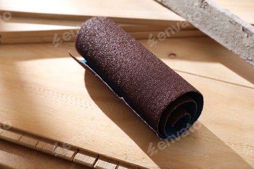 Preview: One rolled sheet of sandpaper on wooden planks