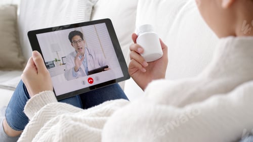 Preview: Over shoulder view of young asia woman talk to doctor on cellphone videocall conference