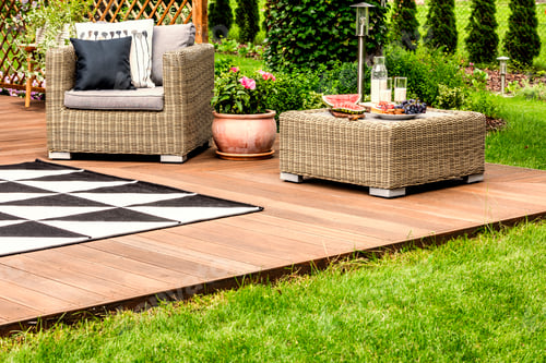 Preview: Flowers between rattan armchair and table with fruits on veranda