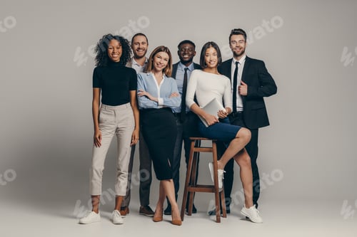 Preview: Happy young business team in formalwear looking at camera while standing on beige background
