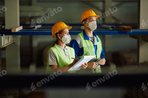 Preview: Warehouse workers with protective face masks checking stock in a storage room.
