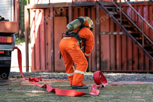 Preview: Fireman wear fire protection suite and oxygen tank exercise roll water hose connect with fire truck