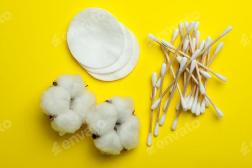 Preview: Cotton swabs, pads and flowers on yellow background