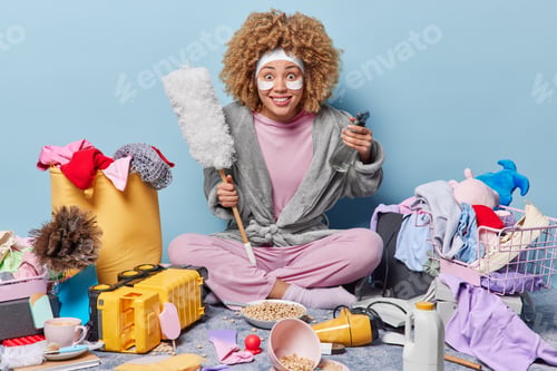 Preview: Smiling housewife looks with glad surprised expression holds dusting brush and spraying bottle ready