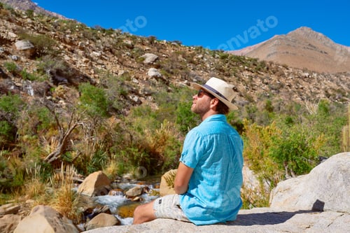 Preview: male sitting on a rock relaxingly contemplating the landscape of the Cochiguaz Valley