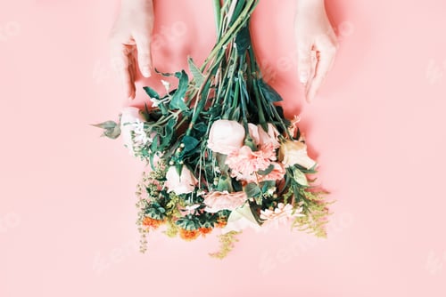 Preview: Beautiful bouquet and female hands on a pink background top view.