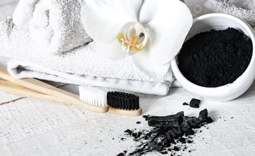 Preview: Close up of black natural teeth whitening powder and toothbrushes.