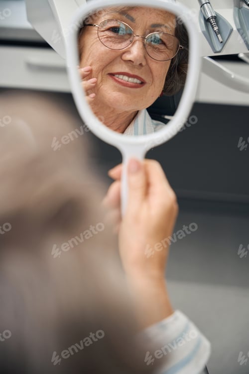 Preview: Elderly woman in dentist office with mirror in her hands