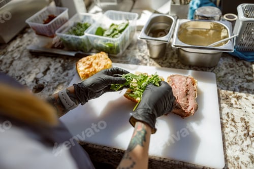 Preview: Skilled Chef Preparing a Fresh and Delicious Sandwich Loaded with Greens and Meat Ingredients
