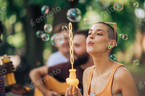 Preview: Portrait of a hippie woman blowing bubbles in park.
