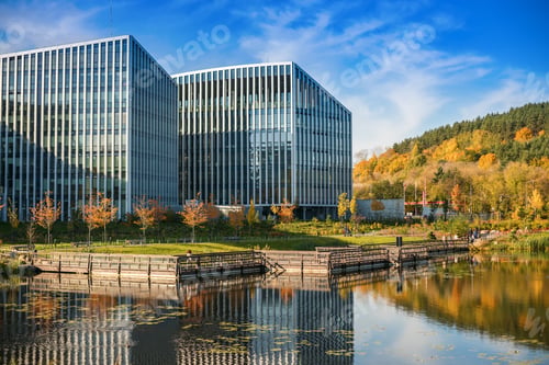 Preview: A reflective glass building rises beside a serene body of water