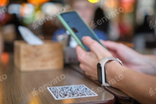 Preview: Closeup of guest hand ordering meal in restaurant while scanning qr code
