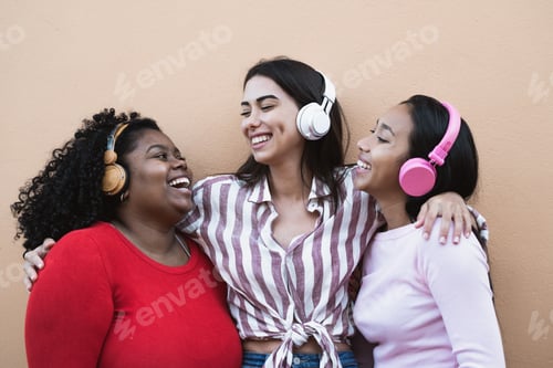 Preview: Happy multiracial friends having fun listening music with wireless headphones outdoor