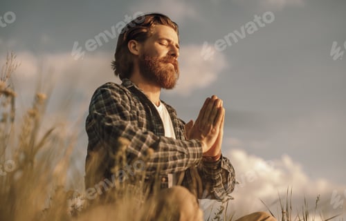 Preview: Adult man meditating in summer field