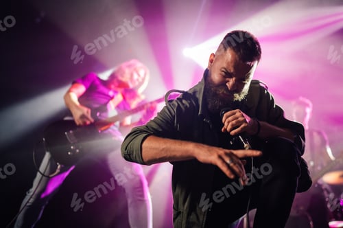 Preview: Singer performing with passion on stage with guitarist in background